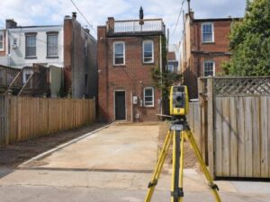 washington-dc-alley-property-lot-survey - Washington DC Land Surveying Survey tripod positioned at a narrow alley entrance leading to a vacant lot behind Washington, DC brick rowhouses.